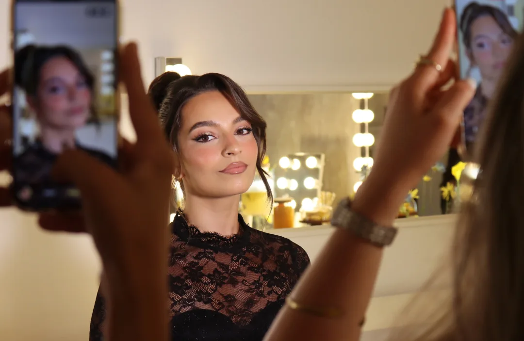 Modelo a ser fotografada ao espelho no fim de uma aula de maquilhagem