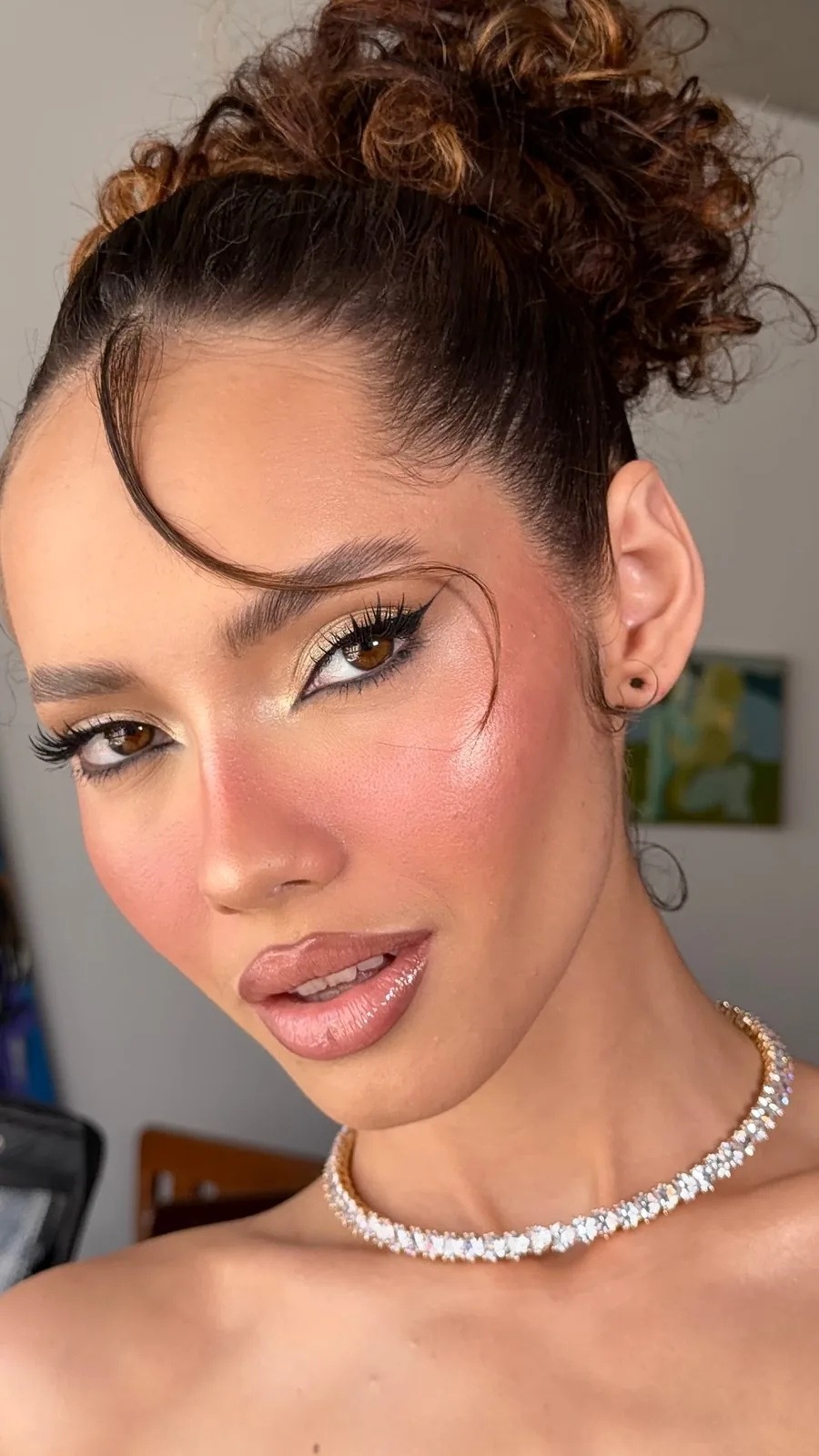 Event makeup with a rosy blush, defined liner and curls gathered in an updo, with a crystal choker