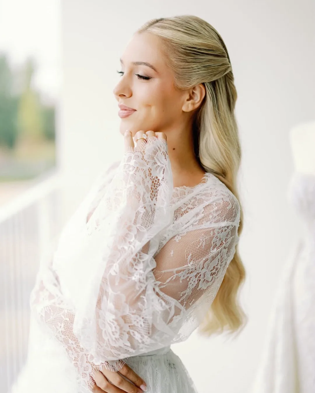Noiva com maquilhagem natural e cabelo apanhado, junto a uma janela